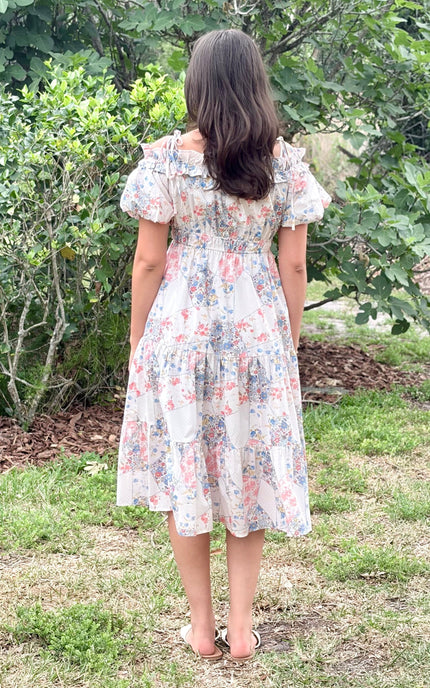 Back view of floral print off-shoulder midi dress showing tiered skirt silhouette and adjustable shoulder straps