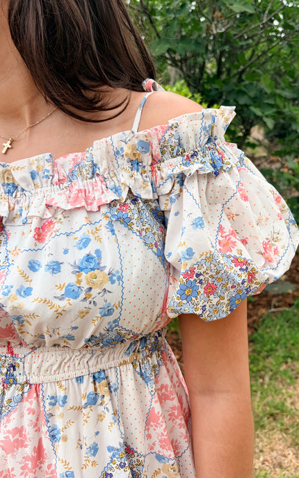Close-up of elastic ruffled off-shoulder neckline with adjustable tying shoulder straps and short puff sleeves on floral midi dress