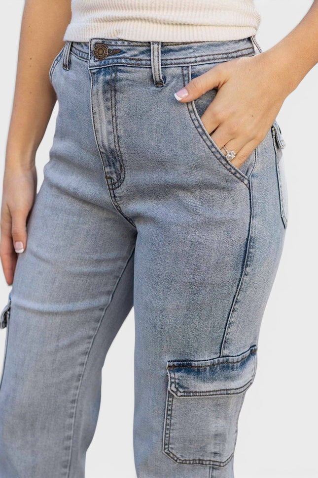 Close-up of a person wearing light blue denim cargo jeans with a cream ribbed top, showing the front and side pockets against a plain light background.