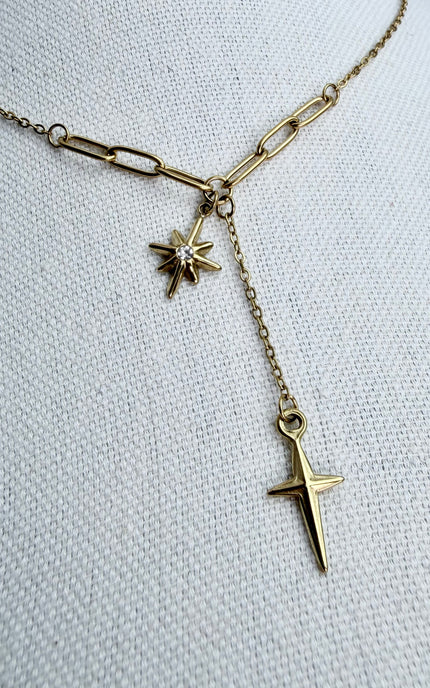 Close‑up of the pendant trio on a jewelry form, highlighting the star, cross, and tassel details.