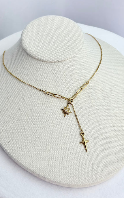 Small gold cross pendant displayed on form with polished finish.