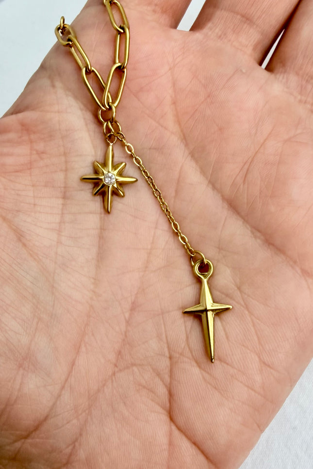 Close‑up of star, cross, and tassel pendants cradled in a hand, highlighting detail and shine.