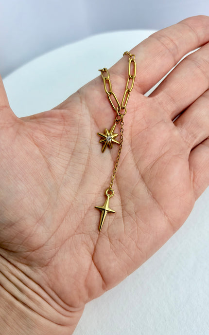 Close‑up of star, cross, and tassel pendants cradled in a hand, highlighting detail and shine.