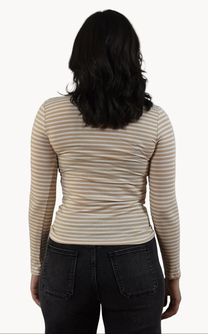 Person wearing a striped long-sleeve shirt and dark pants on a plain background
