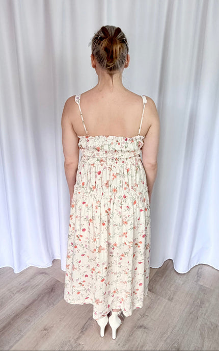 Back view of floral midi dress with adjustable straps and flowy tiered silhouette.