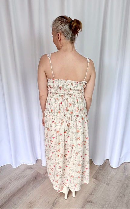 Women's floral midi dress back view showcasing airy fabric and comfortable shirred bodice structure.