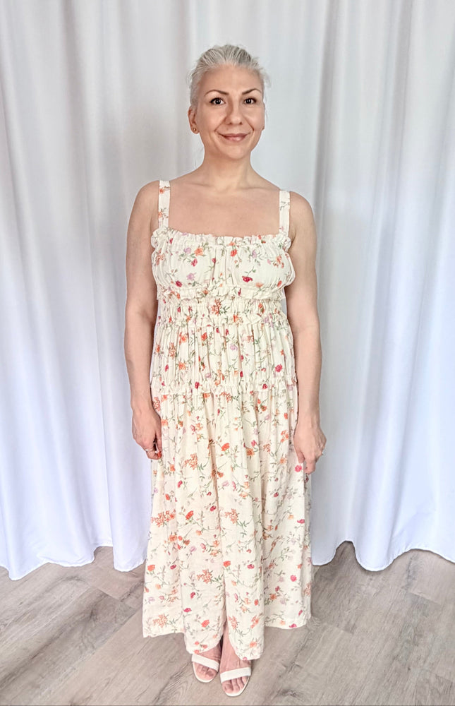 Front view of women's floral midi dress featuring a sweetheart neckline, ruffled trim, and tiered shirred bodice.