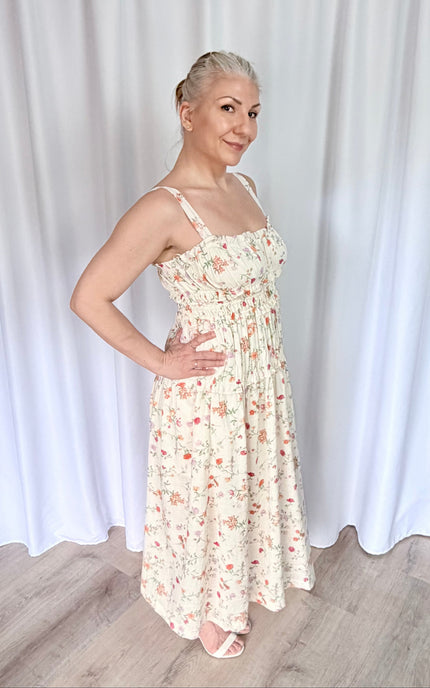 Women's floral midi dress from side view highlighting shirred bodice and soft drape.