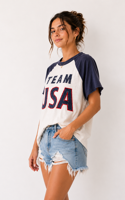Woman wearing a 'Team USA' t-shirt and denim shorts against a white background
