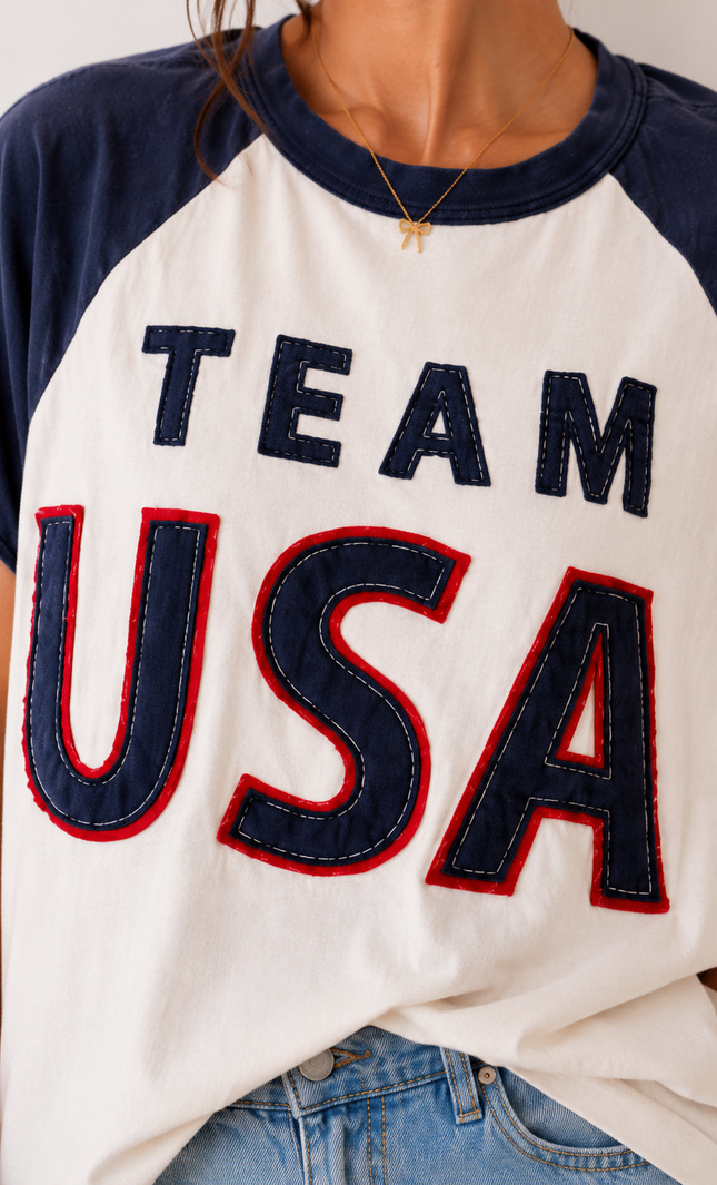 White t-shirt with 'TEAM USA' text in blue and red, worn by a person.
