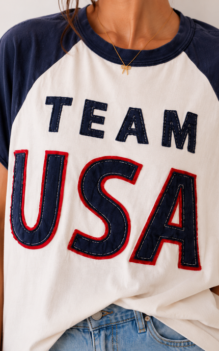 White t-shirt with 'TEAM USA' text in blue and red, worn by a person.