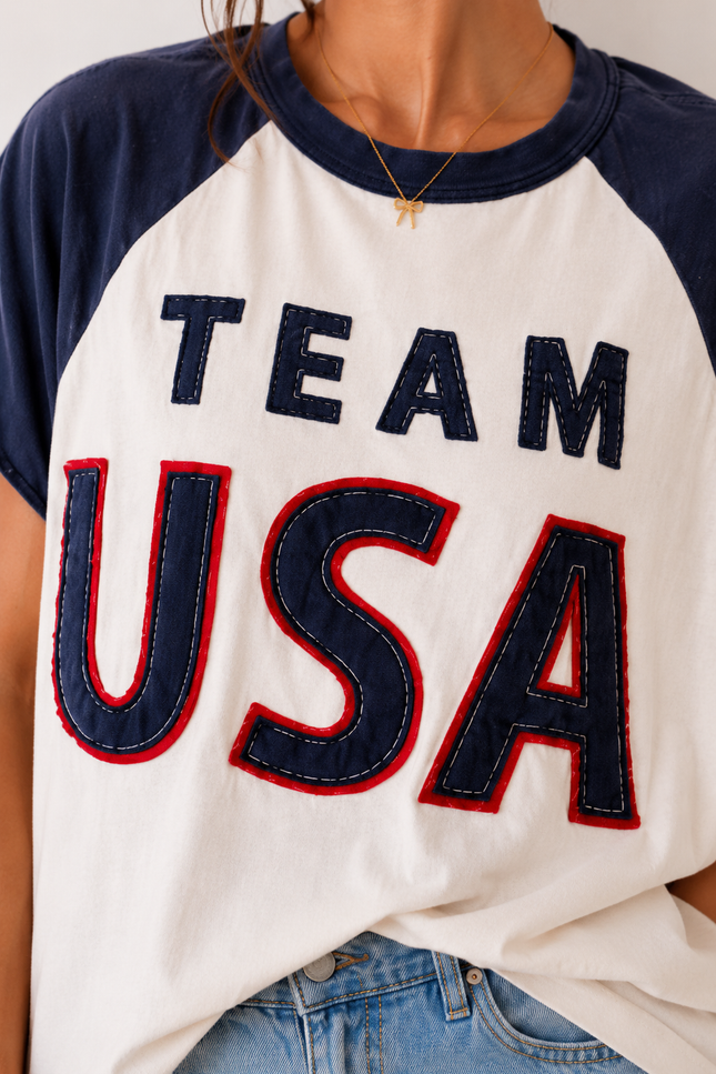 White t-shirt with 'TEAM USA' text in blue and red, worn by a person.