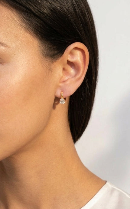 Model wearing delicate gold hoop earrings with sparkling teardrop crystal charms.