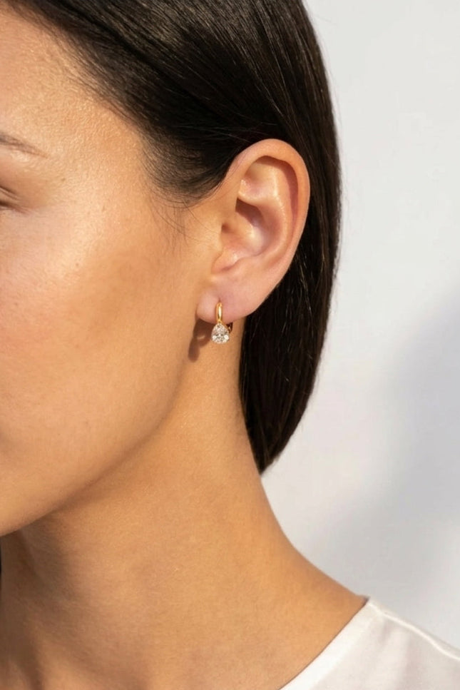 Model wearing delicate gold hoop earrings with sparkling teardrop crystal charms.