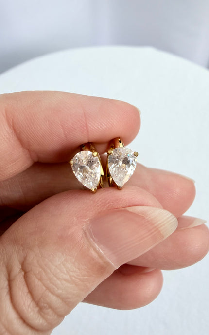 Women's gold hoop earrings with polished teardrop crystal accents.
