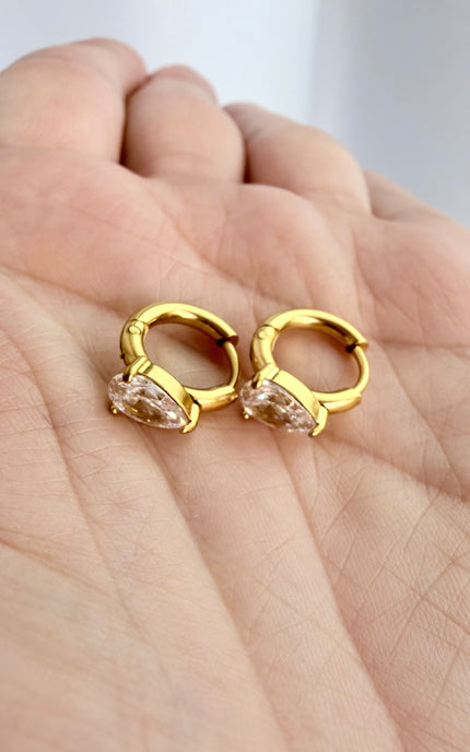 Close-up of gold hoop earrings with brilliant teardrop cubic zirconia accents.