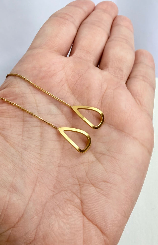 Delicate gold open-triangle threader earrings held in a palm to showcase their featherlight 1g weight, minimal geometric design, and bright gold finish in natural light.