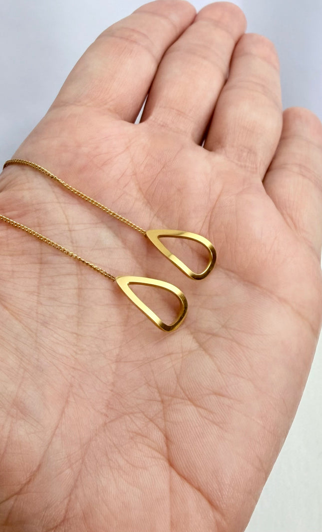 Delicate gold open-triangle threader earrings held in a palm to showcase their featherlight 1g weight, minimal geometric design, and bright gold finish in natural light.