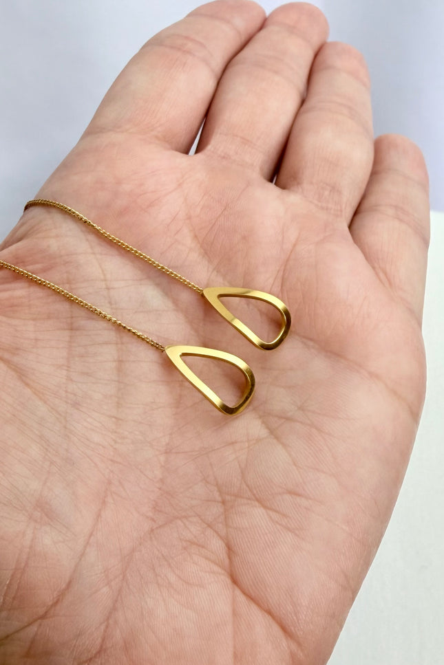 Delicate gold open-triangle threader earrings held in a palm to showcase their featherlight 1g weight, minimal geometric design, and bright gold finish in natural light.