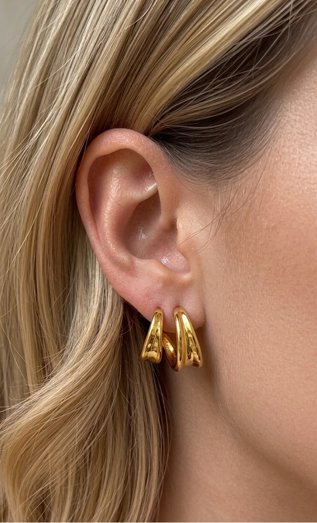 On-ear shot of double twist hoop earrings in 18k gold PVD over stainless steel showing dimensional twist detail