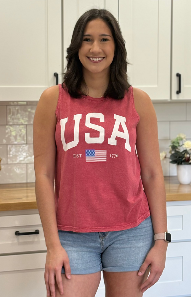 Person wearing a red 'USA' tank top with an American flag in a kitchen setting