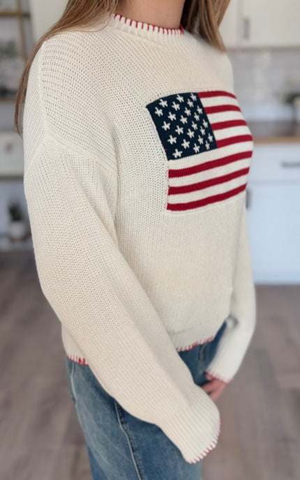 Model wearing American flag knit sweater with relaxed fit and long sleeves