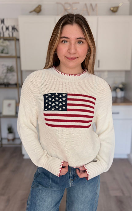 Model wearing American flag knit sweater with relaxed fit and long sleeves