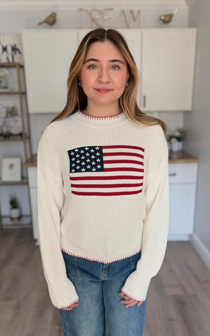 Model wearing American flag knit sweater with relaxed fit and long sleeves