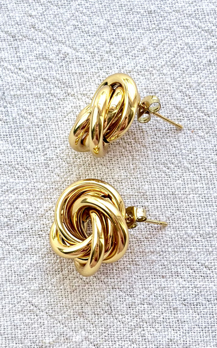 Aurelia gold knot stud earrings on soft linen background with warm natural light