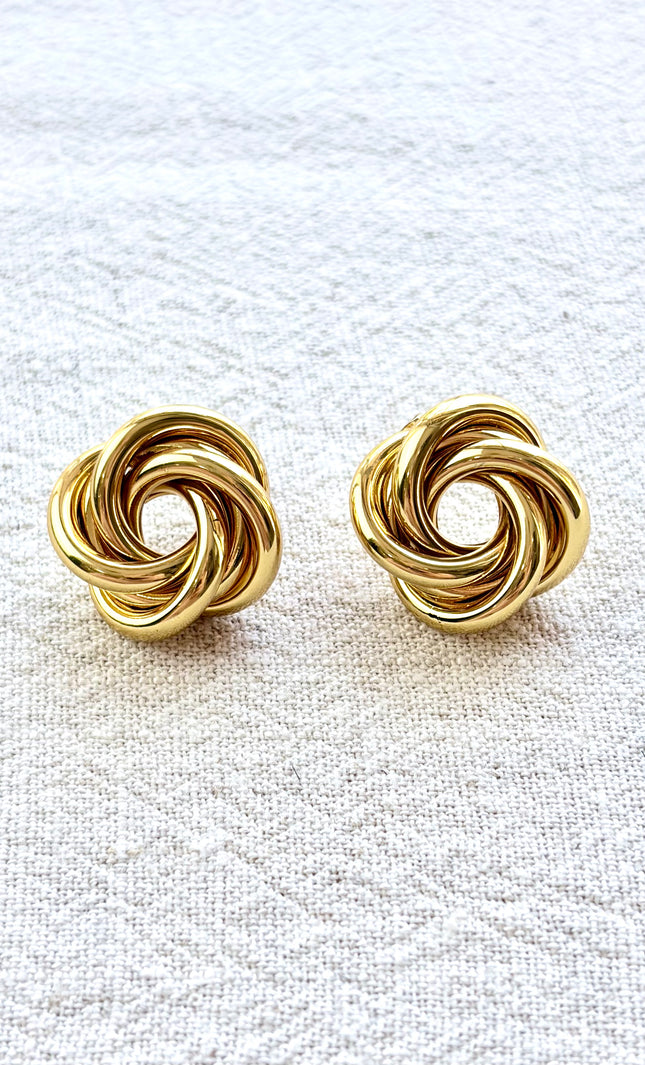Aurelia gold knot stud earrings on soft linen background with warm natural light, timeless everyday jewelry