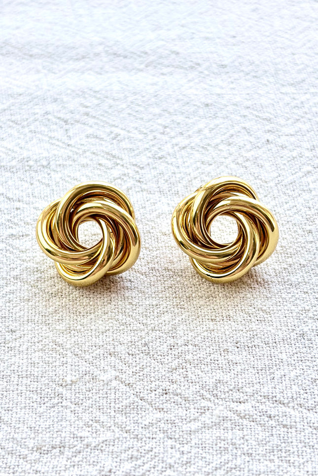 Aurelia gold knot stud earrings on soft linen background with warm natural light, timeless everyday jewelry