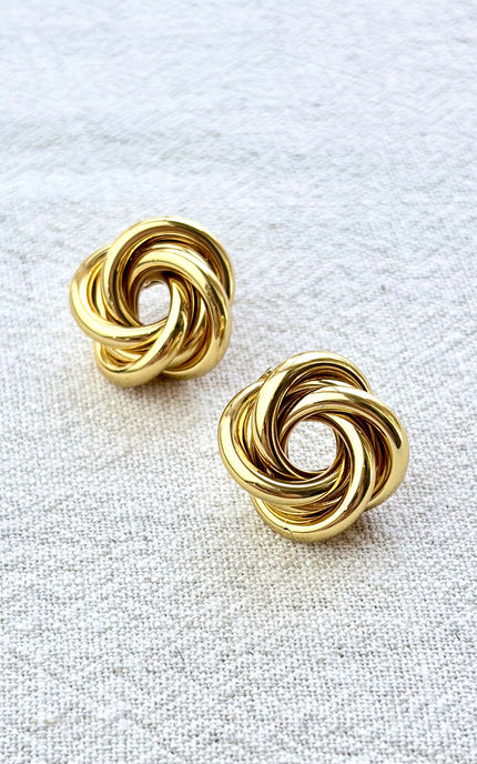 Aurelia gold knot stud earrings on soft linen background with warm natural light, timeless everyday jewelry