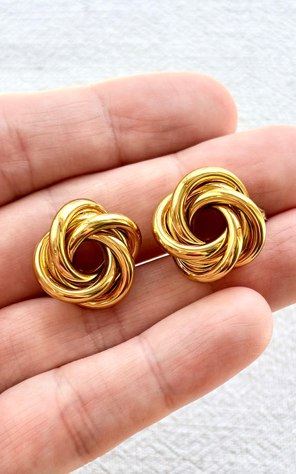 Aurelia gold knot stud earrings on soft linen background with warm natural light