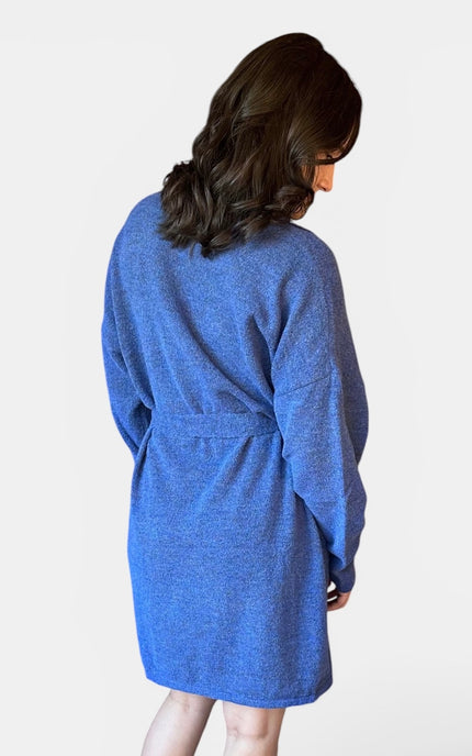 A woman wearing a heathered blue knit dress shown from the back against a plain white studio background.