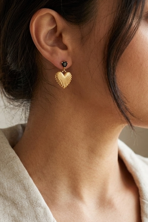 Black crystal heart drop earrings with textured 18k gold detail worn on model showing feminine, edgy styling