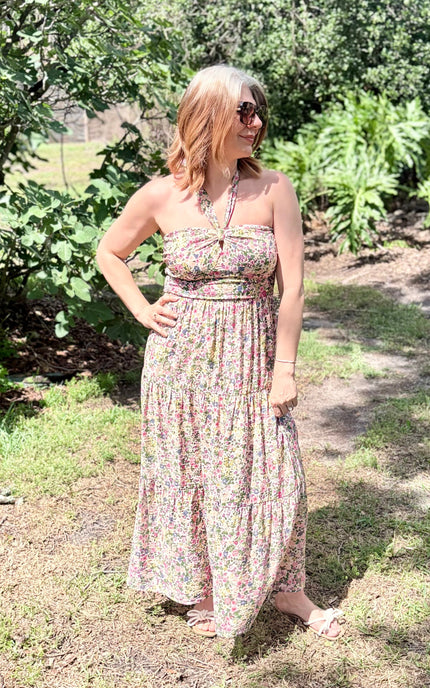 Full-length front view of the Catalina Floral Knot Maxi Dress from Justyna Grace Boutique, captured in natural outdoor light to highlight the vibrant floral print and flowing tiered skirt.