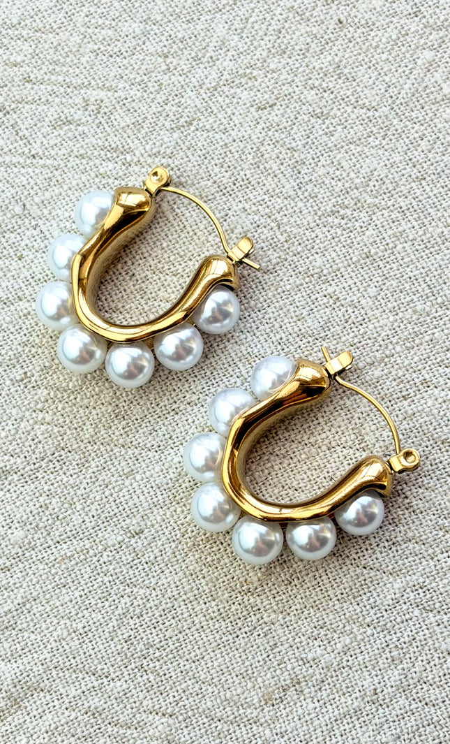 Celeste pearl hoop earrings with gold finish on soft linen background in natural light