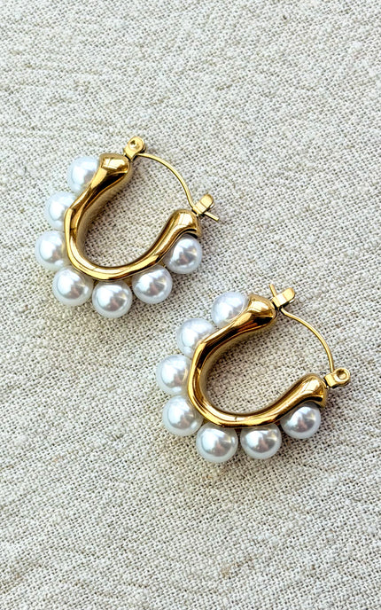 Celeste pearl hoop earrings with gold finish on soft linen background in natural light