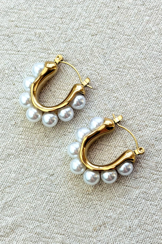 Celeste pearl hoop earrings with gold finish on soft linen background in natural light
