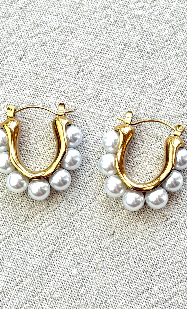 Celeste pearl hoop earrings with gold finish on soft linen background in natural light