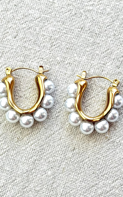 Celeste pearl hoop earrings with gold finish on soft linen background in natural light
