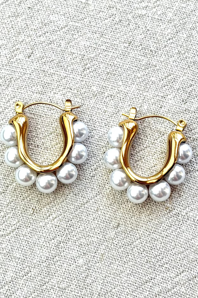 Celeste pearl hoop earrings with gold finish on soft linen background in natural light