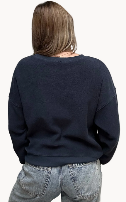 Cozy pullover sweatshirt with a relaxed fit, dropped dolman sleeves, and a bold contrast stripe detail, photographed on a soft-linen background.