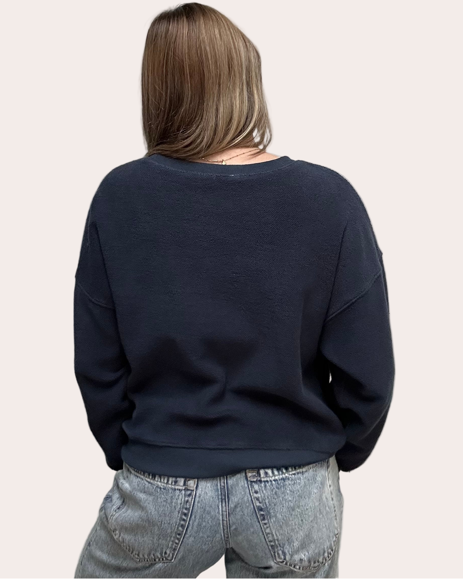 Cozy pullover sweatshirt with a relaxed fit, dropped dolman sleeves, and a bold contrast stripe detail, photographed on a soft-linen background.