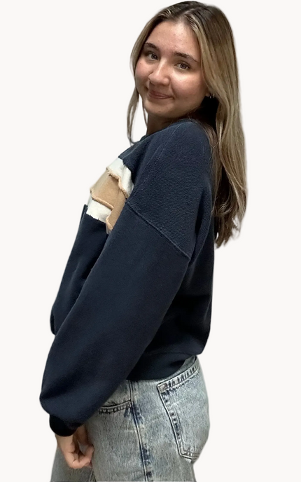 Cozy pullover sweatshirt with a relaxed fit, dropped dolman sleeves, and a bold contrast stripe detail, photographed on a soft-linen background.
