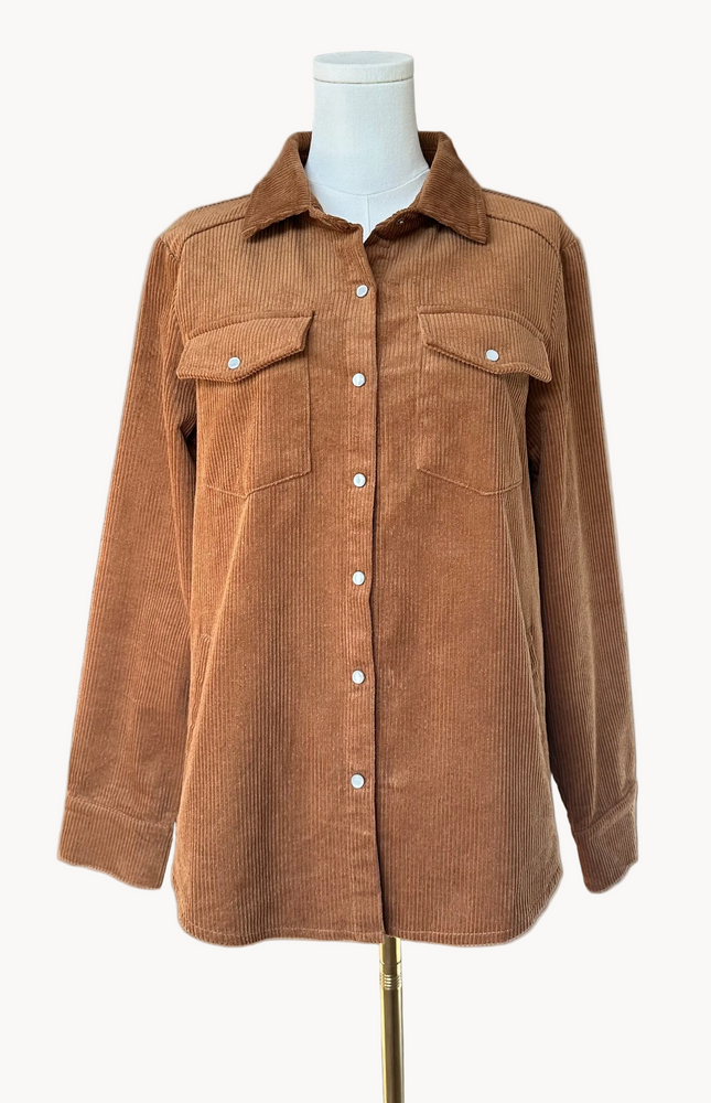 Soft corduroy button-down shacket with a relaxed fit and side pockets, shown in a neutral tone against a clean soft-linen background, styled as a cozy layering piece.
