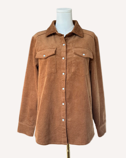 Soft corduroy button-down shacket with a relaxed fit and side pockets, shown in a neutral tone against a clean soft-linen background, styled as a cozy layering piece.