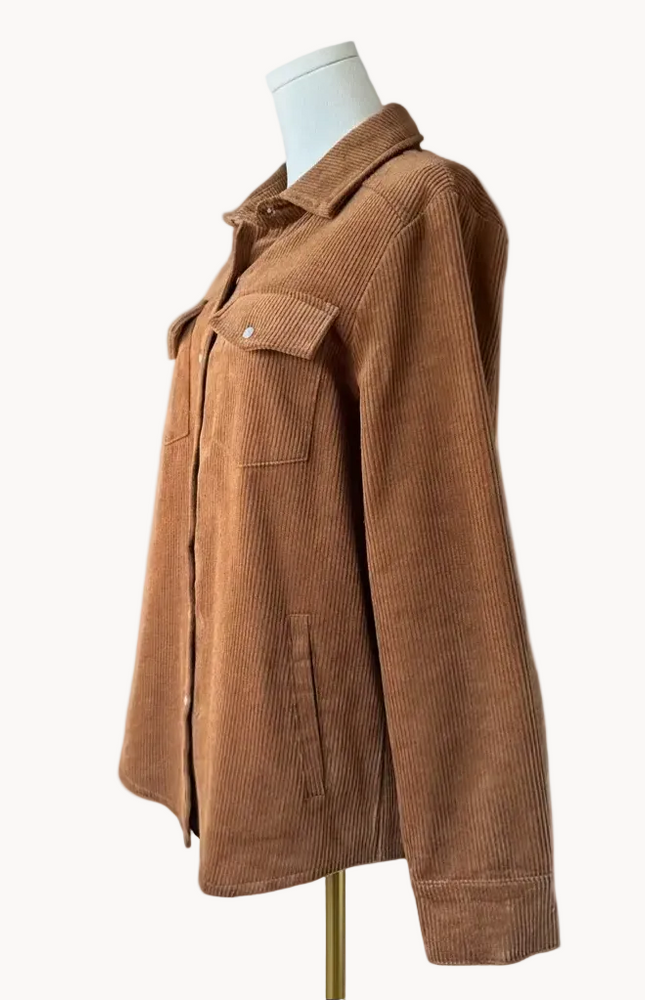 Soft corduroy button-down shacket with a relaxed fit and side pockets, shown in a neutral tone against a clean soft-linen background, styled as a cozy layering piece.
