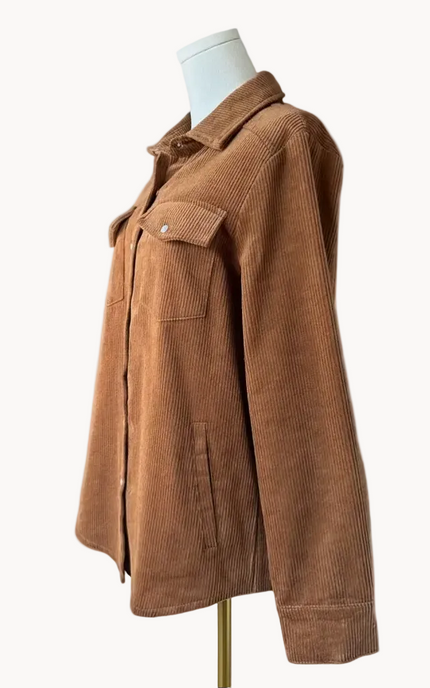 Soft corduroy button-down shacket with a relaxed fit and side pockets, shown in a neutral tone against a clean soft-linen background, styled as a cozy layering piece.
