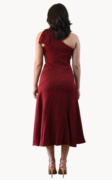 Cranberry Grace Dress with one-shoulder bow detail, slanted seamwork, and flared midi hem, designed for elegant movement, photographed on Soft Linen background.
